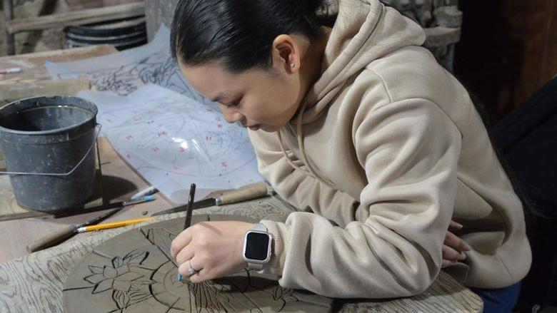 Student creating a ceramic tile